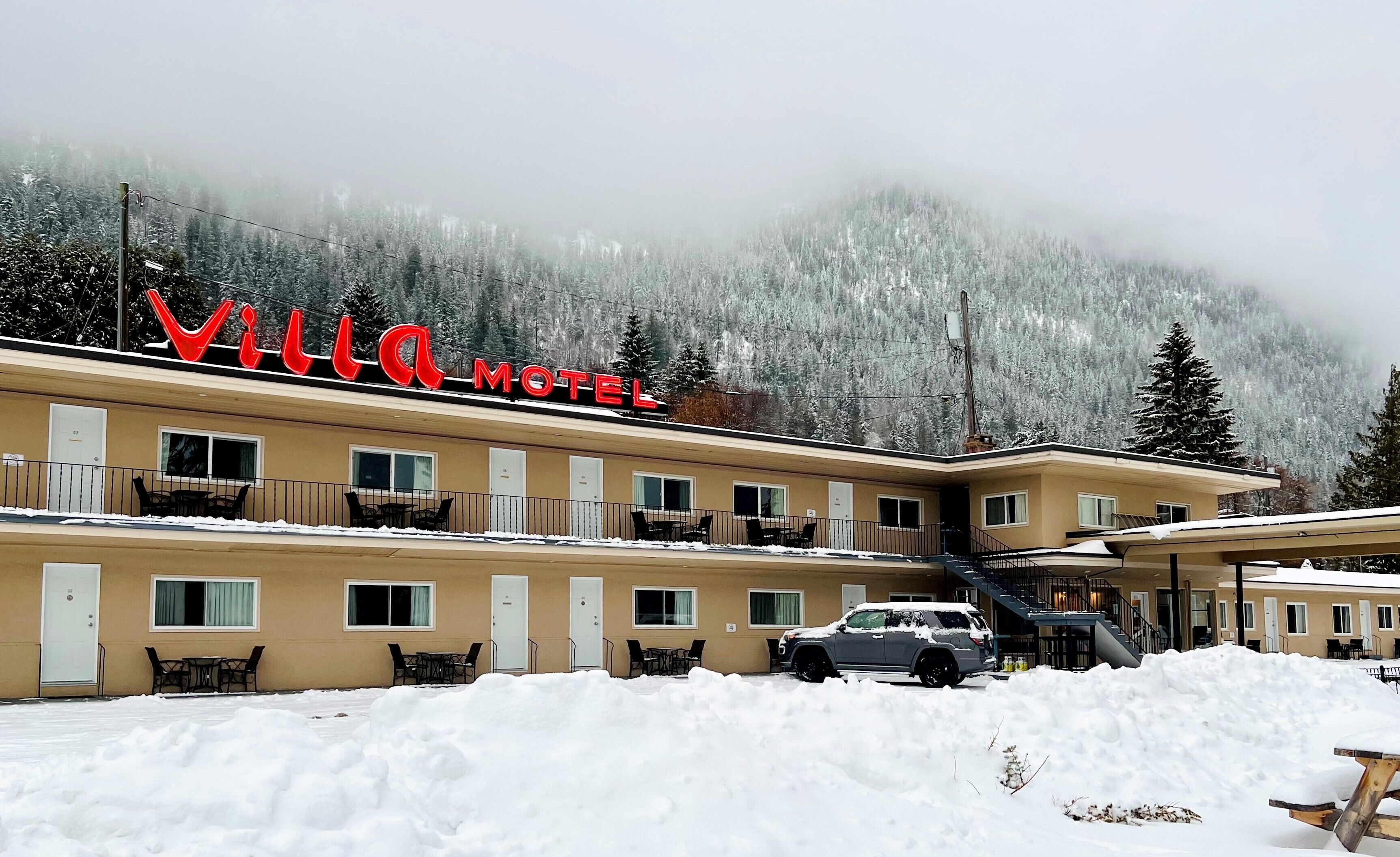A VILLA HOTEL with a snow-covered exterior, multiple balconies, and a mountainous backdrop.