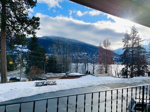 Paisatge nevós amb una muntanya al fons, un camí amb una tanca i un cotxe estacionat.
