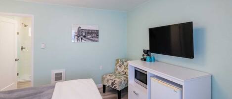 A bedroom with a bed, a TV, a chair, and a dresser.