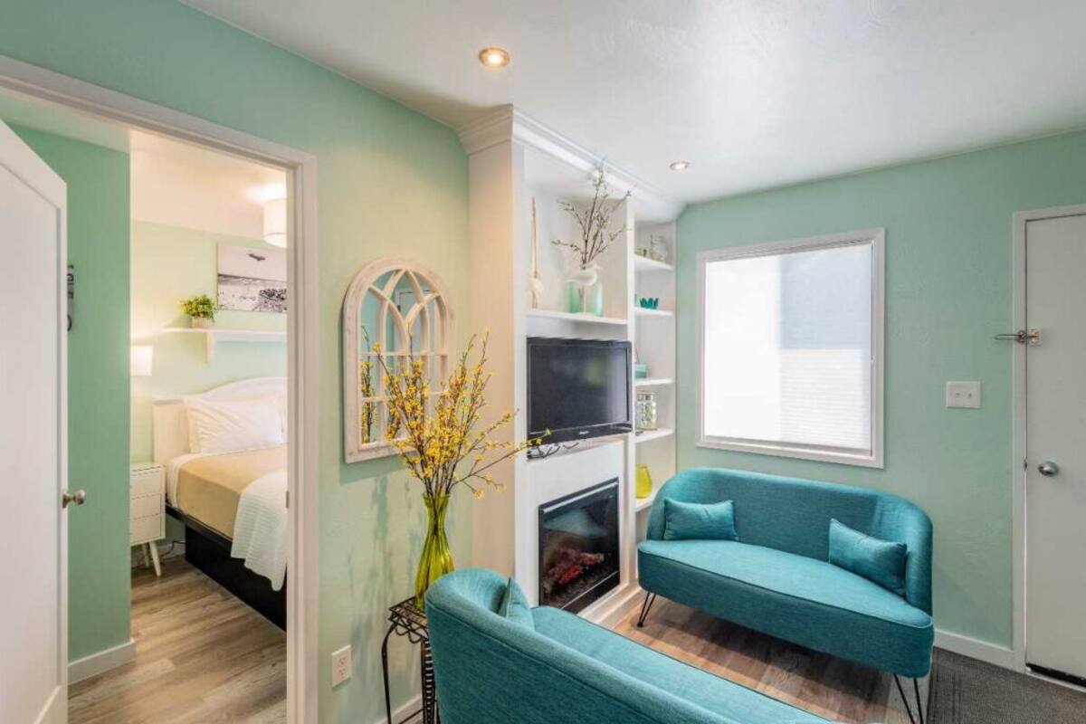 A room with teal walls, a fireplace, a teal sofa, and a bed with white bedding.
