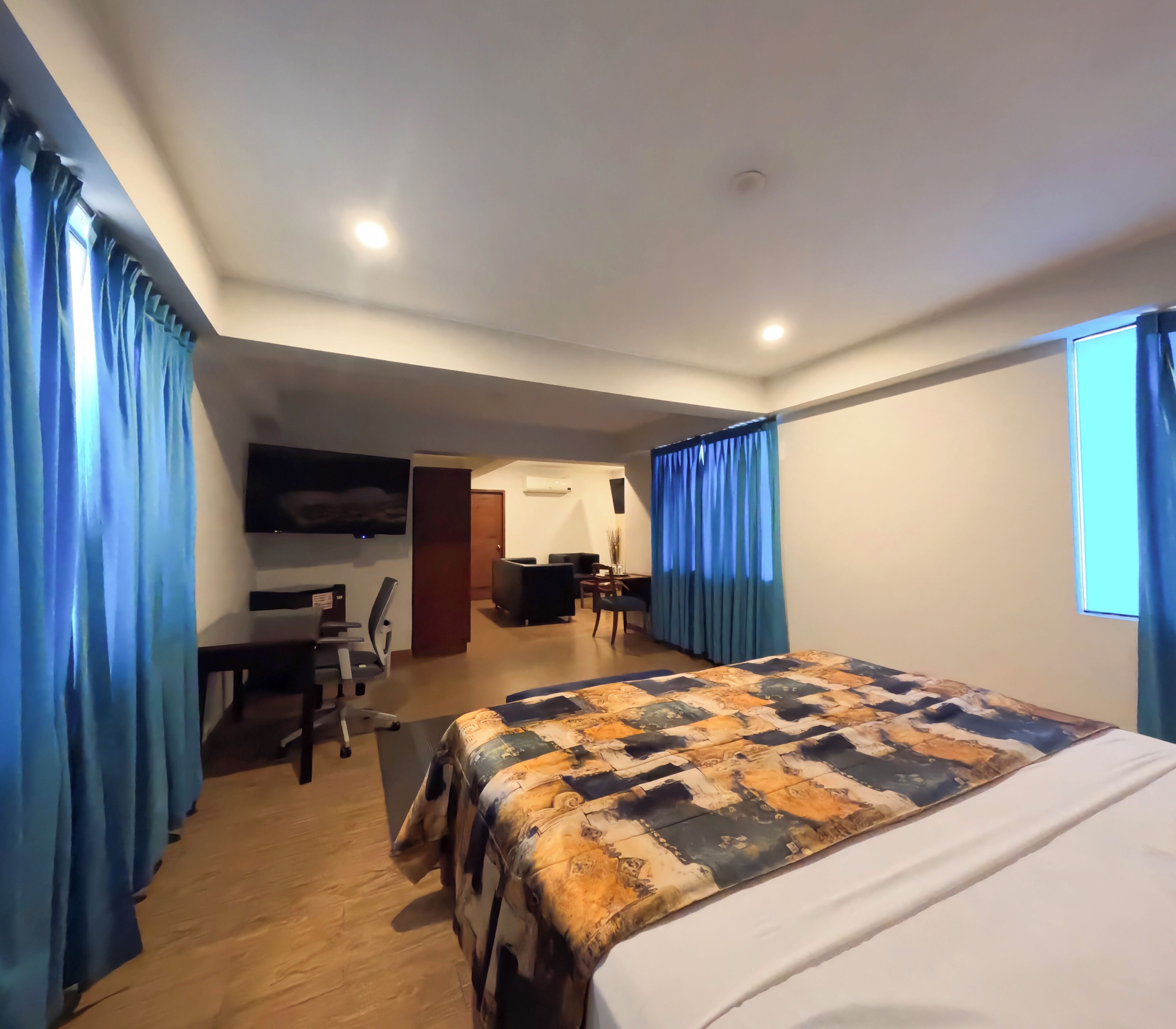 Una habitación de hotel con cama, escritorio, silla y una pequeña zona de kitchenette.