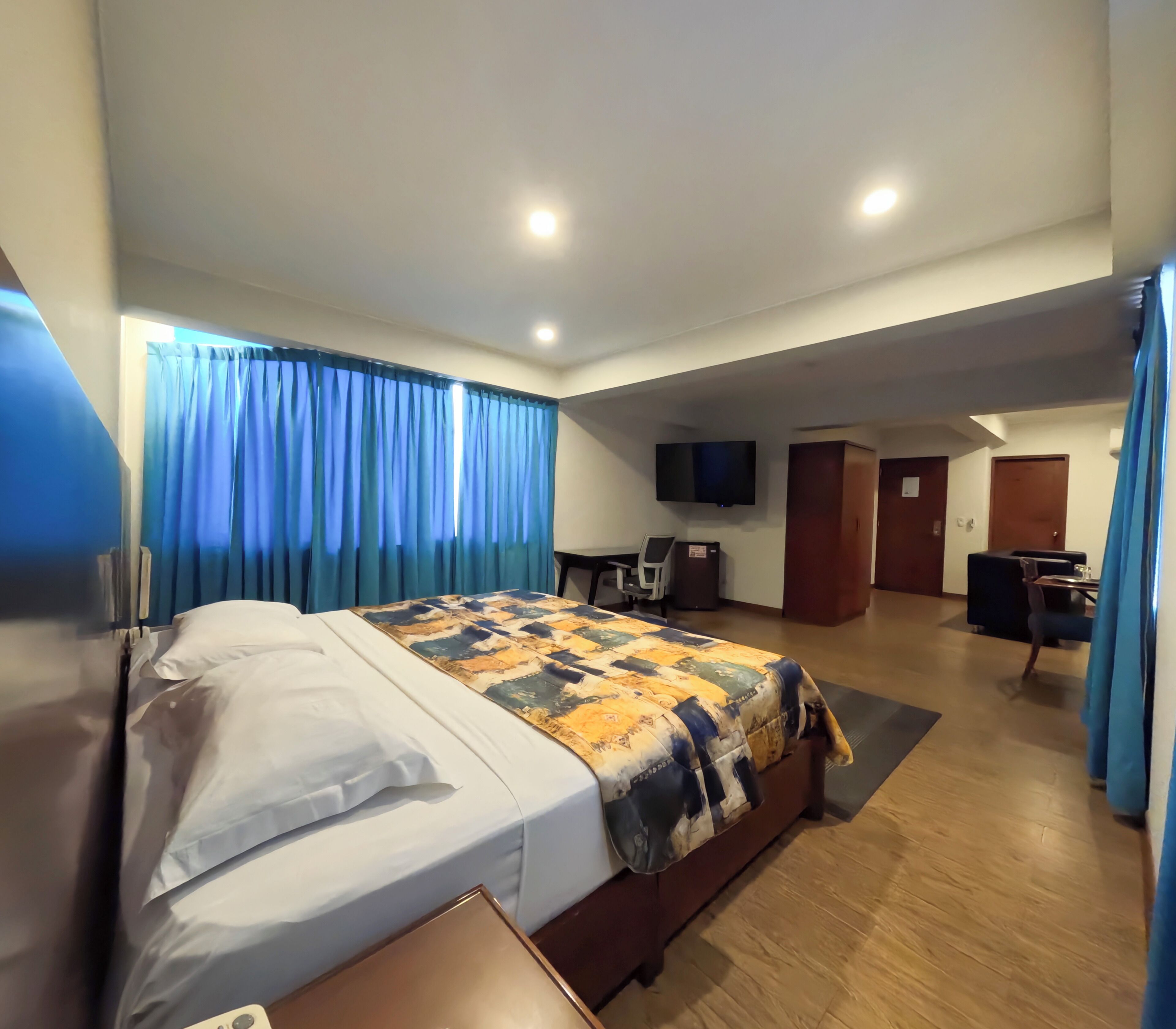 Ein Hotelzimmer mit Bett, Schreibtisch, Stuhl, Fernseher und einer Tür.