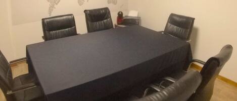 A conference room with a large rectangular table, black leather chairs, and a world map on the wall.