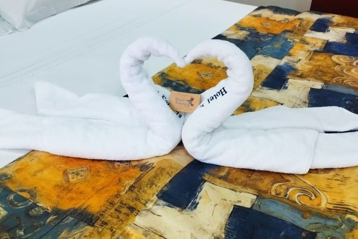 A bed with a heart-shaped towel arrangement and a patterned bedspread.