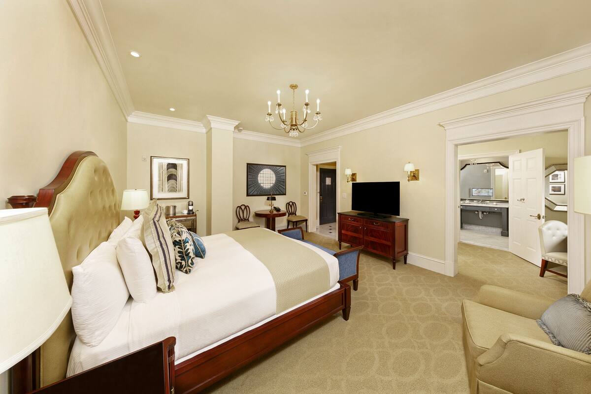 A hotel room with a large bed, a television, a desk, and a chair.