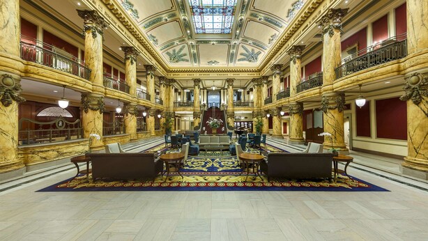A grand lobby with marble columns, a central seating area, and a high ceiling with a skylight. - The Jefferson Hotel (Richmond)