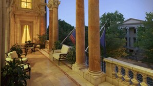 A grand hall with classical architecture, featuring large columns and arches, a seating area with chairs and tables, and a view of a building in the background. - The Jefferson Hotel (Richmond)