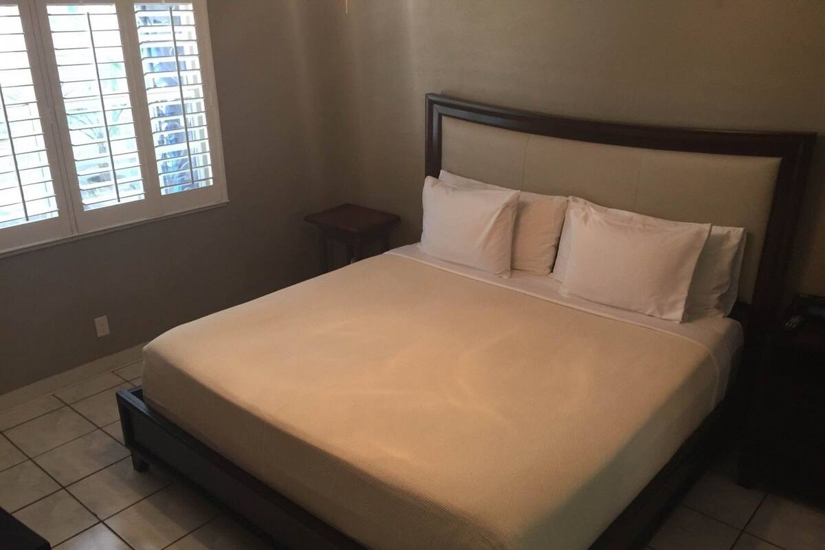 Une chambre à coucher avec un lit, une table de chevet, une petite table et une fenêtre avec des stores.