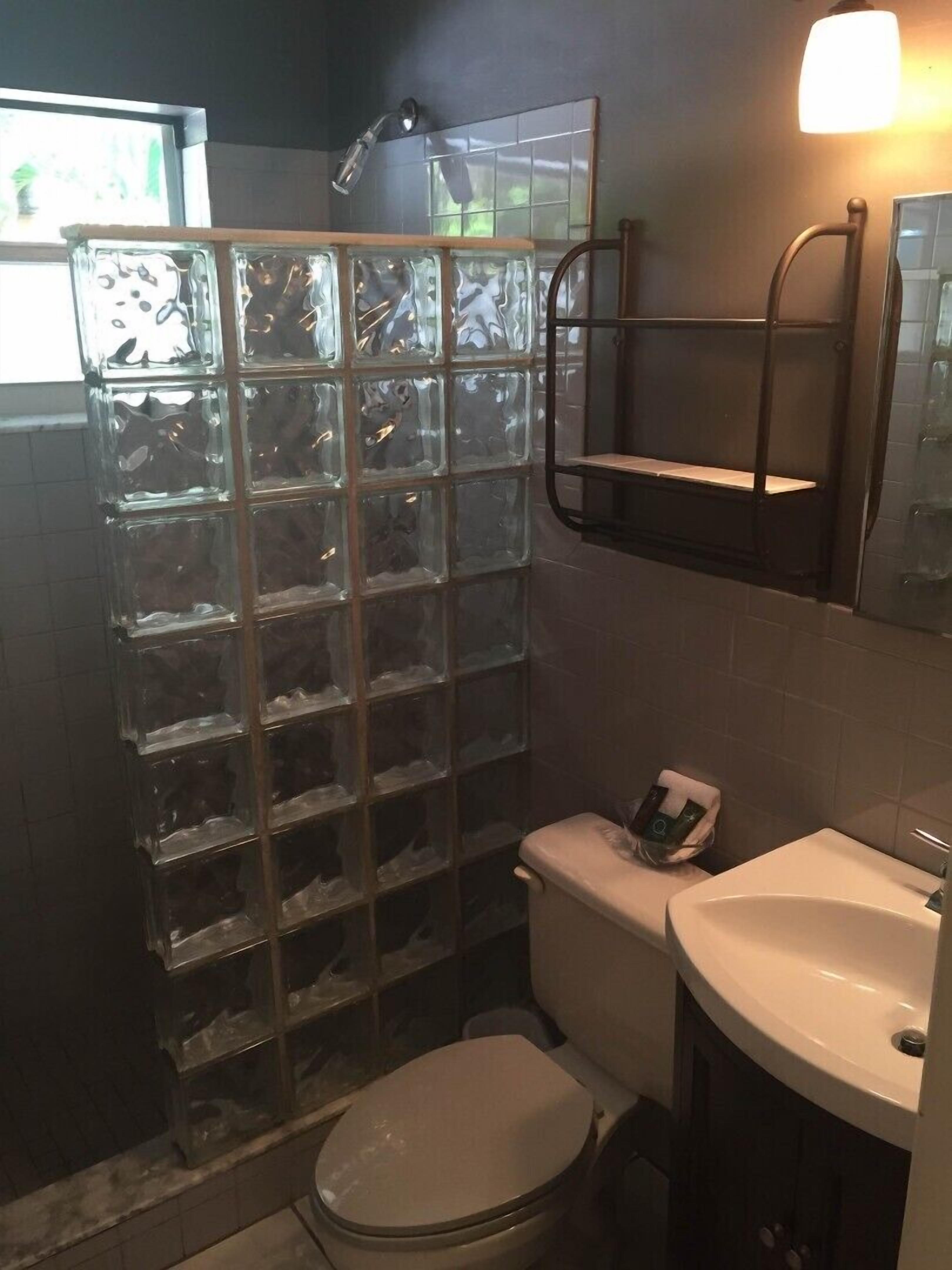 A bathroom with a glass shower enclosure, a toilet, and a sink.