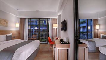 Habitación de hotel con dos camas, un escritorio y una silla. Tiene un televisor montado en la pared y un balcón con cortinas.