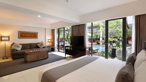 Quarto de hotel moderno com uma cama grande, um sofá, uma TV e vista para uma piscina e jardim.