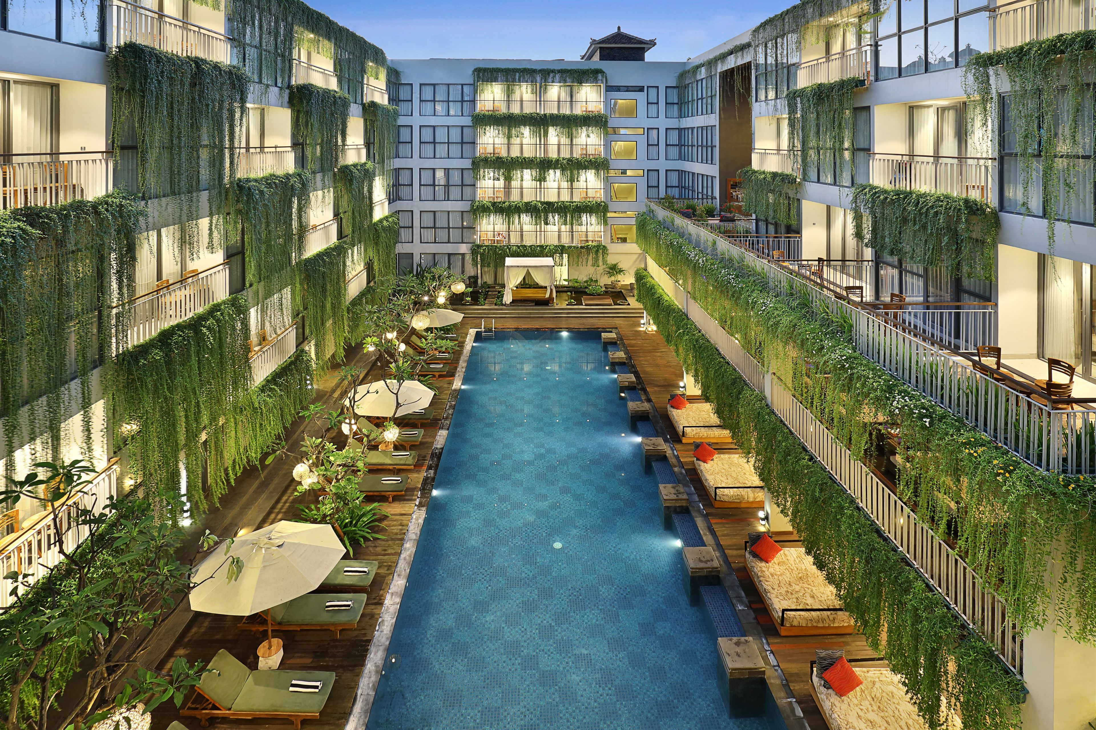 A rooftop pool with lounge areas and greenery.