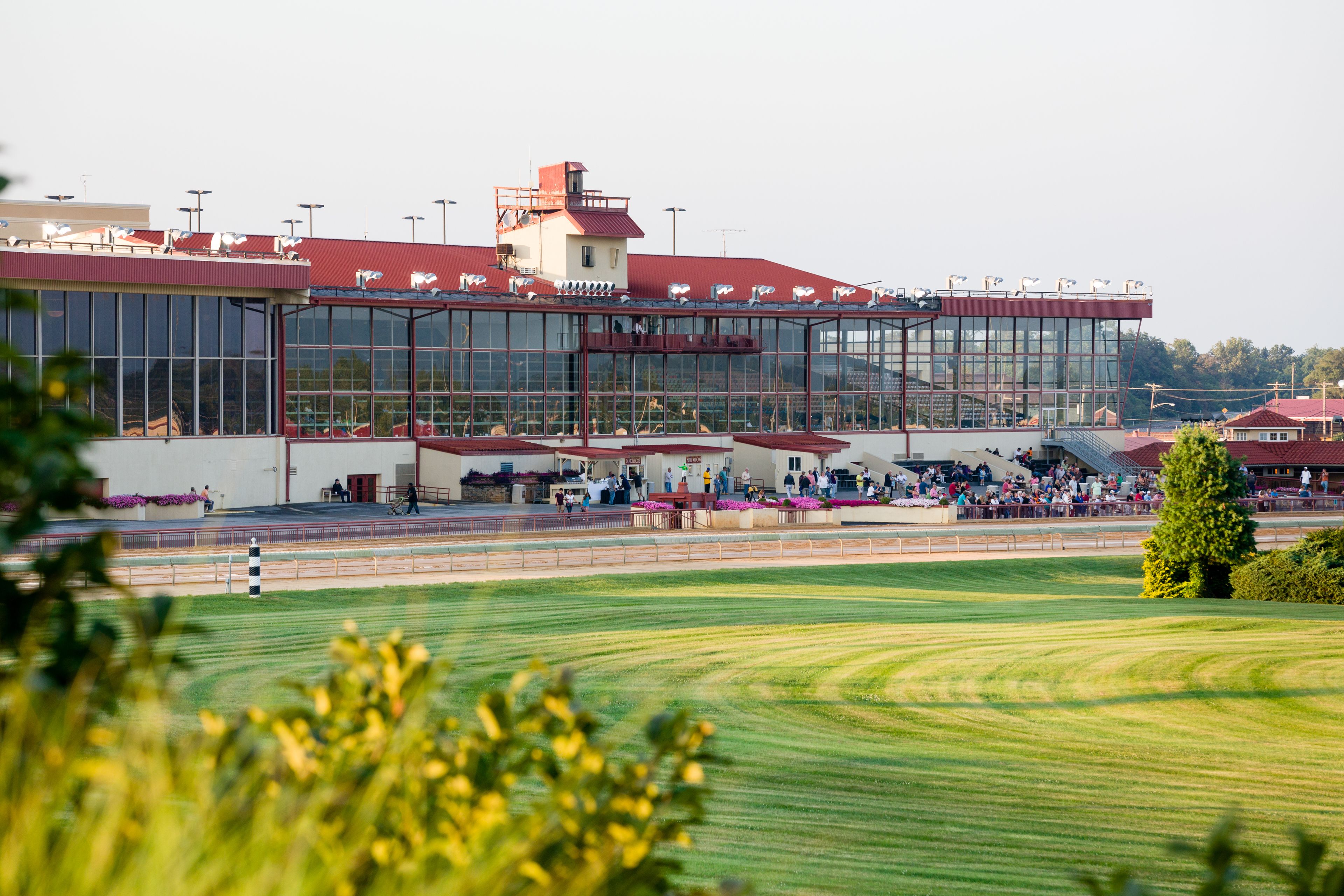 A large building with multiple levels, a covered seating area, and a green field in the foreground.