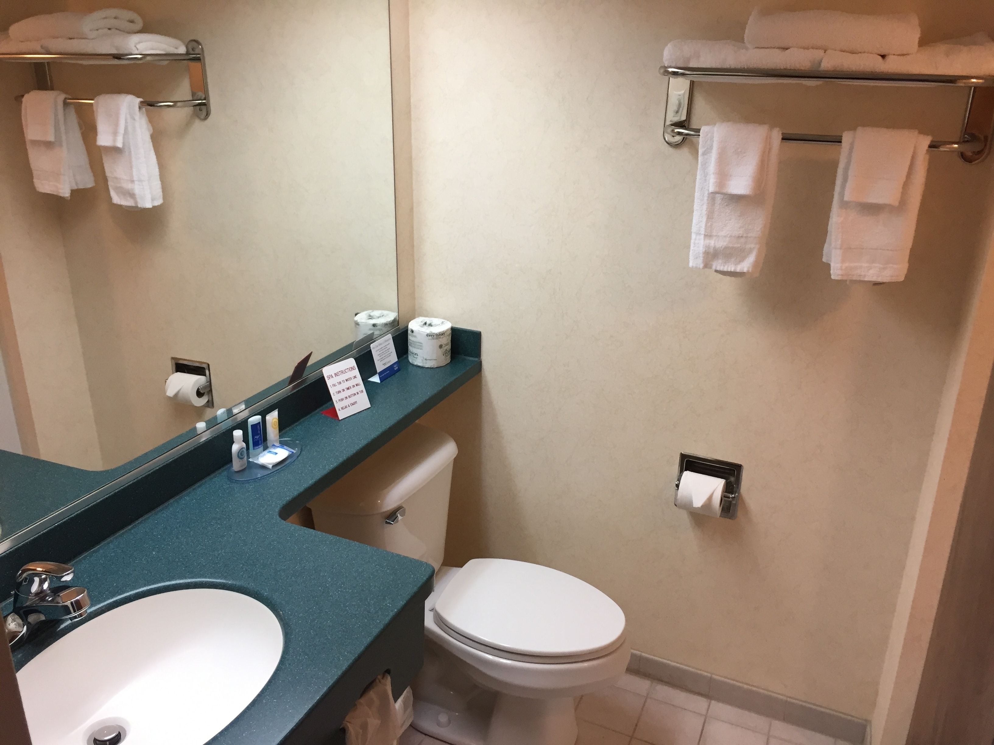 Un baño con lavamanos, inodoro y toalleros.