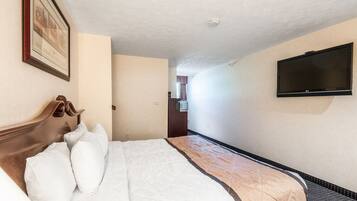 A hotel room with a bed, a television mounted on the wall, and a framed picture on the wall.