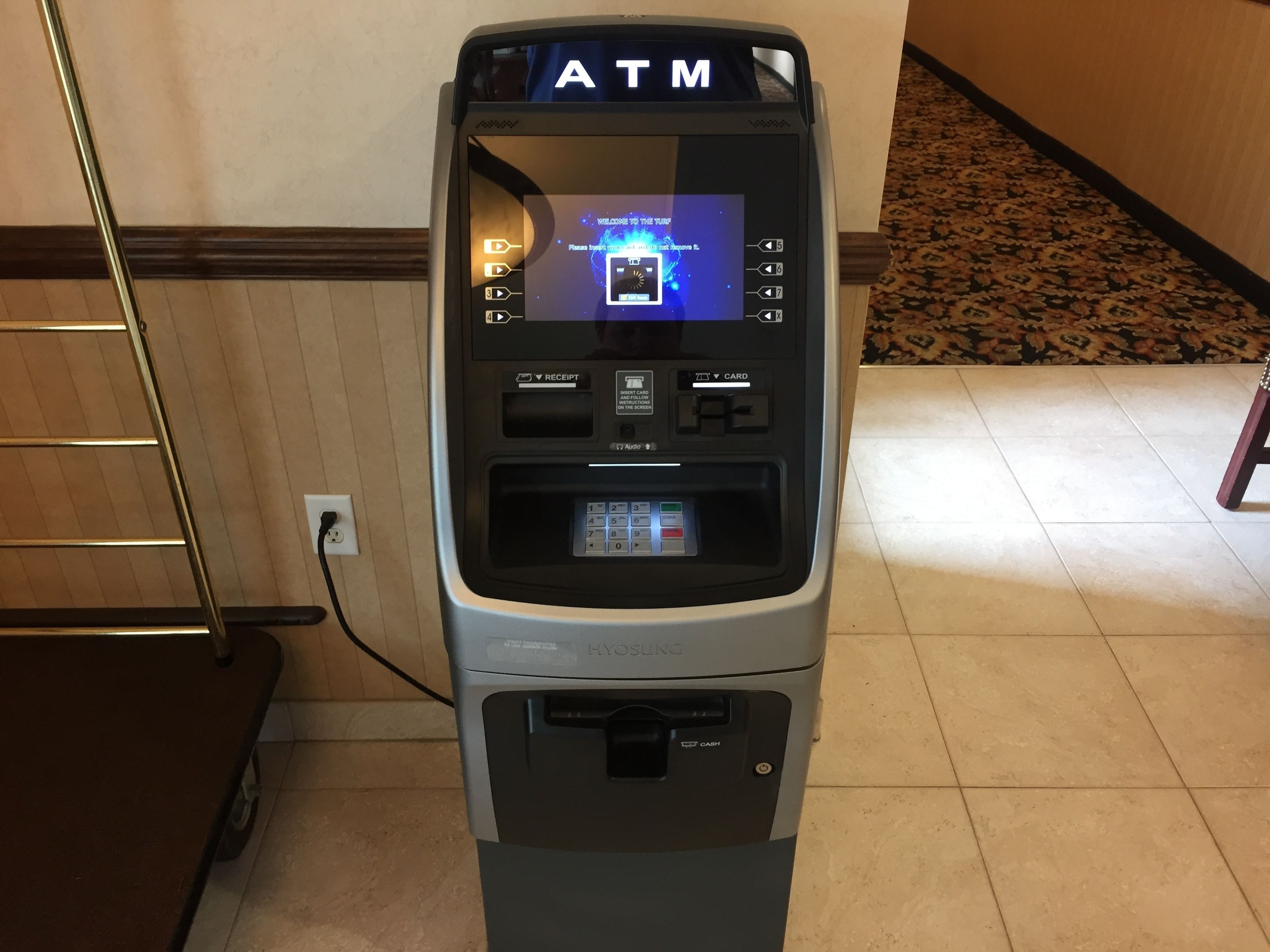 An ATM machine with a touchscreen interface, card slot, and cash withdrawal slot.