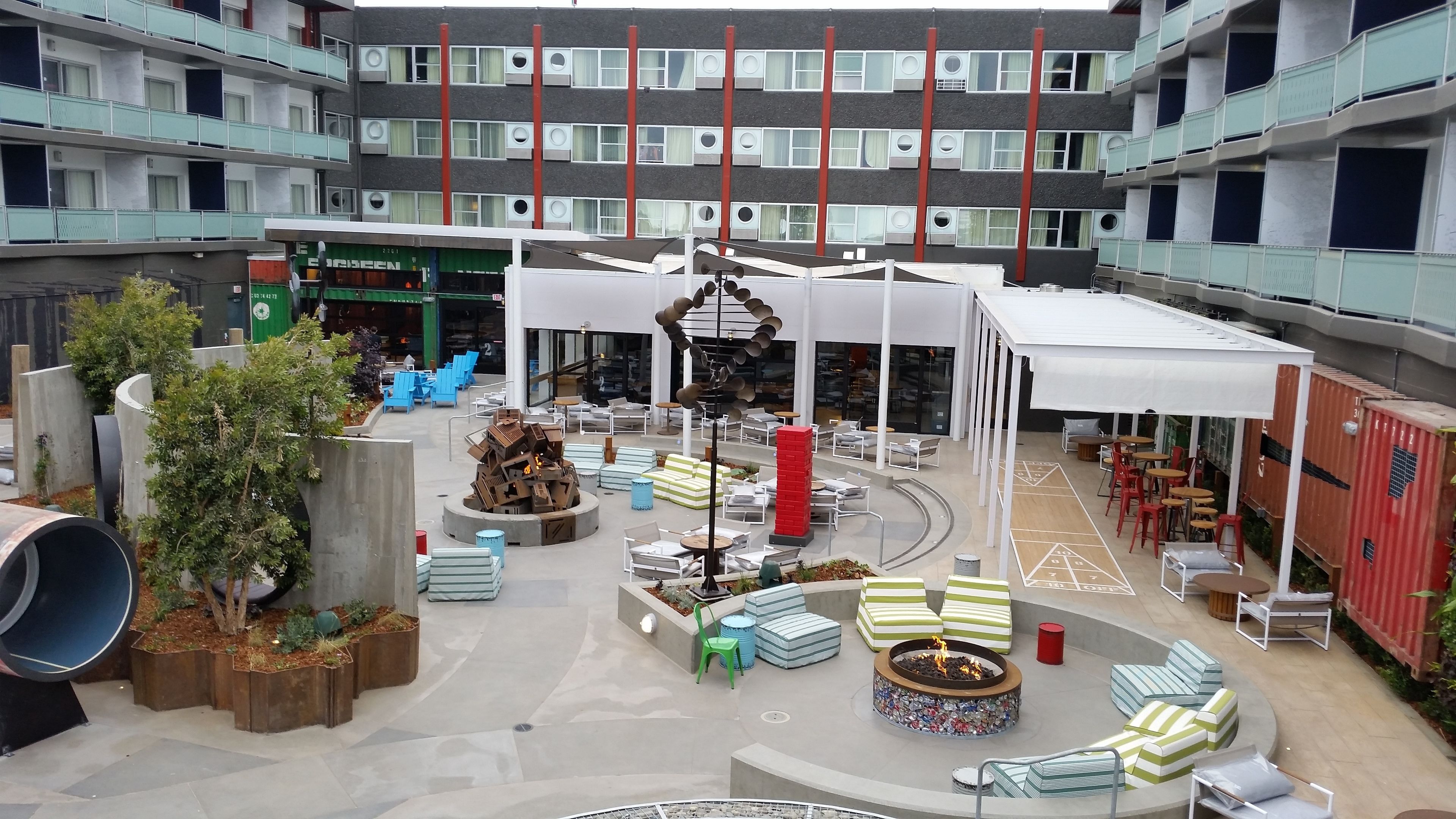 A spacious indoor atrium with multiple seating areas, a central fire pit, and a variety of outdoor furniture.