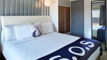 A hotel room with a bed, a wardrobe, a door, and a window.