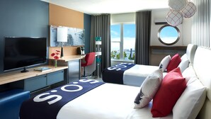 Una habitación de hotel con cama, escritorio, televisor y vistas a la ciudad.