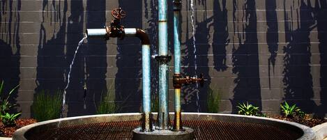 A water fountain with multiple spouts in front of a building with balconies.