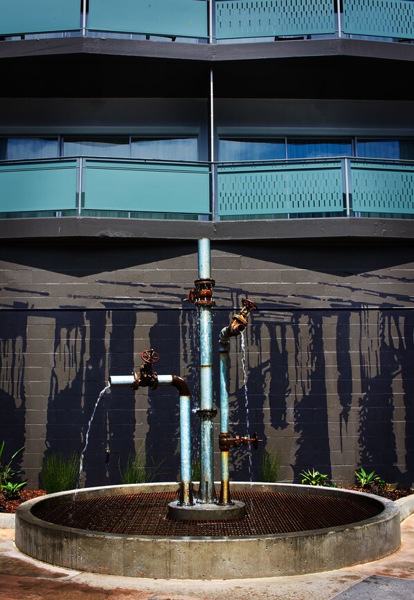 Una fuente de agua con varios chorros frente a un edificio con balcones.