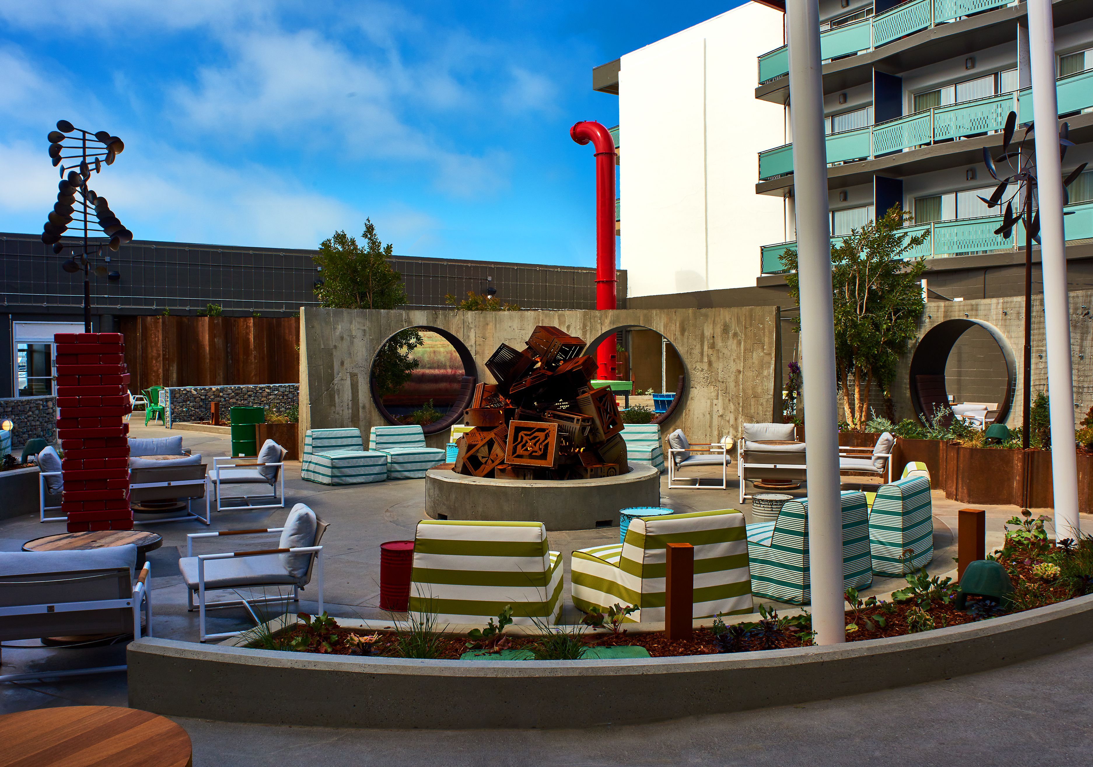 An outdoor seating area with various chairs and tables, surrounded by plants and decorative elements.
