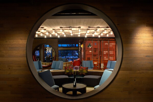 A circular mirror reflecting a modern lounge area with sofas, a coffee table, and a vase with flowers. - Hotel Zephyr San Francisco (San Francisco)