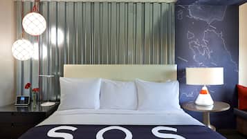 A hotel room with a bed, a nightstand, a lamp, and a map on the wall.