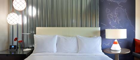 A hotel room with a bed, a nightstand, a lamp, and a map on the wall.