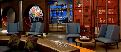 A modern lounge area with seating, a bar, and a large window.