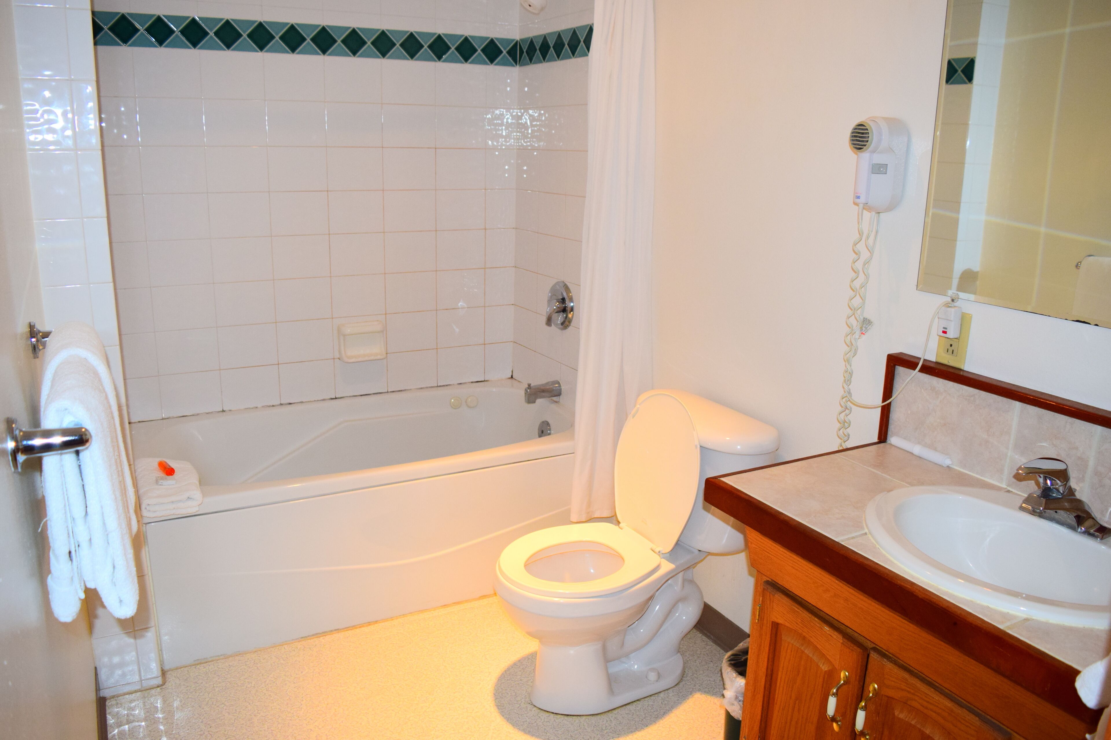 Un bagno con un WC bianco, una vasca, un lavandino e uno specchio.