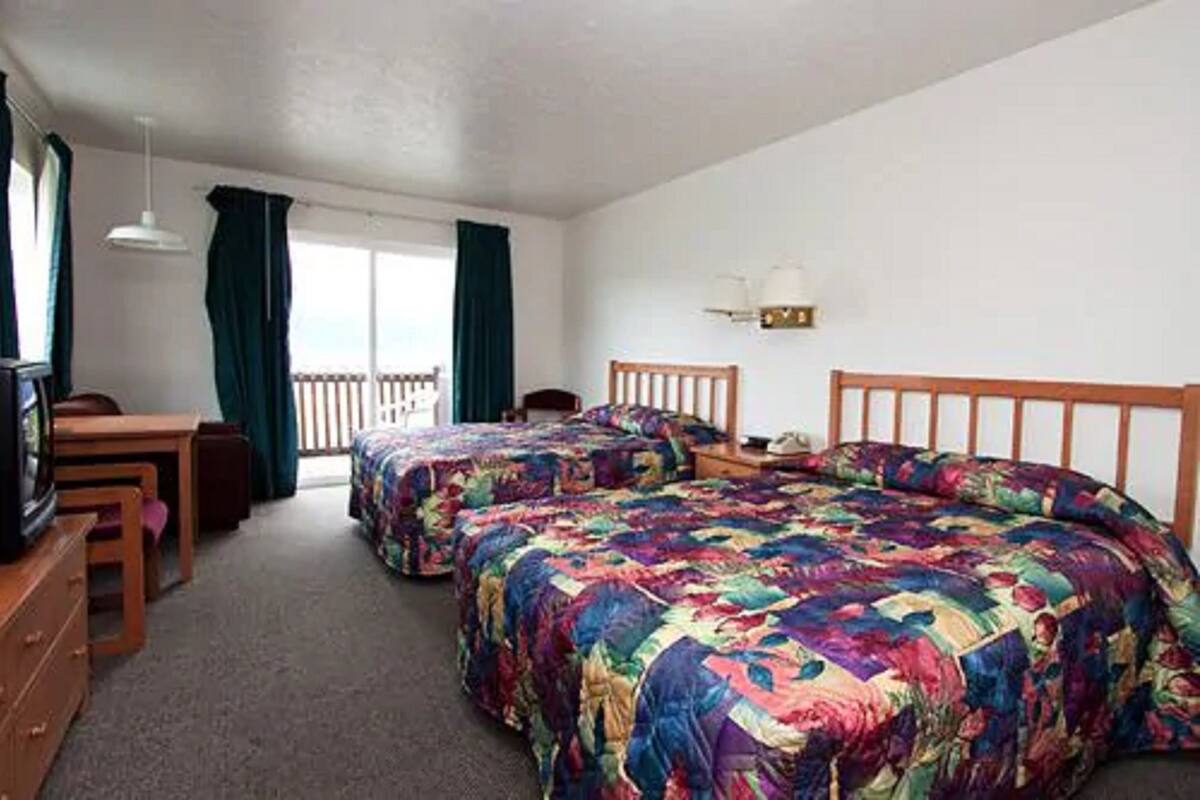 A room with two beds, a desk, a chair, and a television.