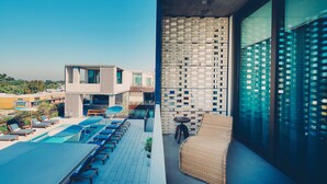 Una terrazza sul tetto con piscina, poltrone da relax e un divano in vimini.