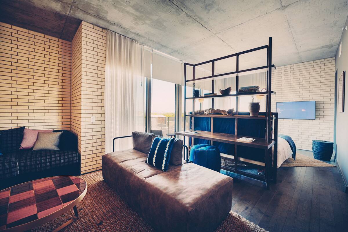 Uma sala de estar moderna com parede de tijolos, um sofá, uma mesa de centro, uma estante e uma televisão.
