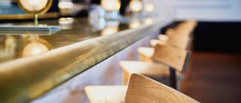 Un bar con una barra pulida y sillas de madera.