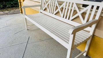 A white bench with a metal frame and slatted seat, placed on a concrete surface.