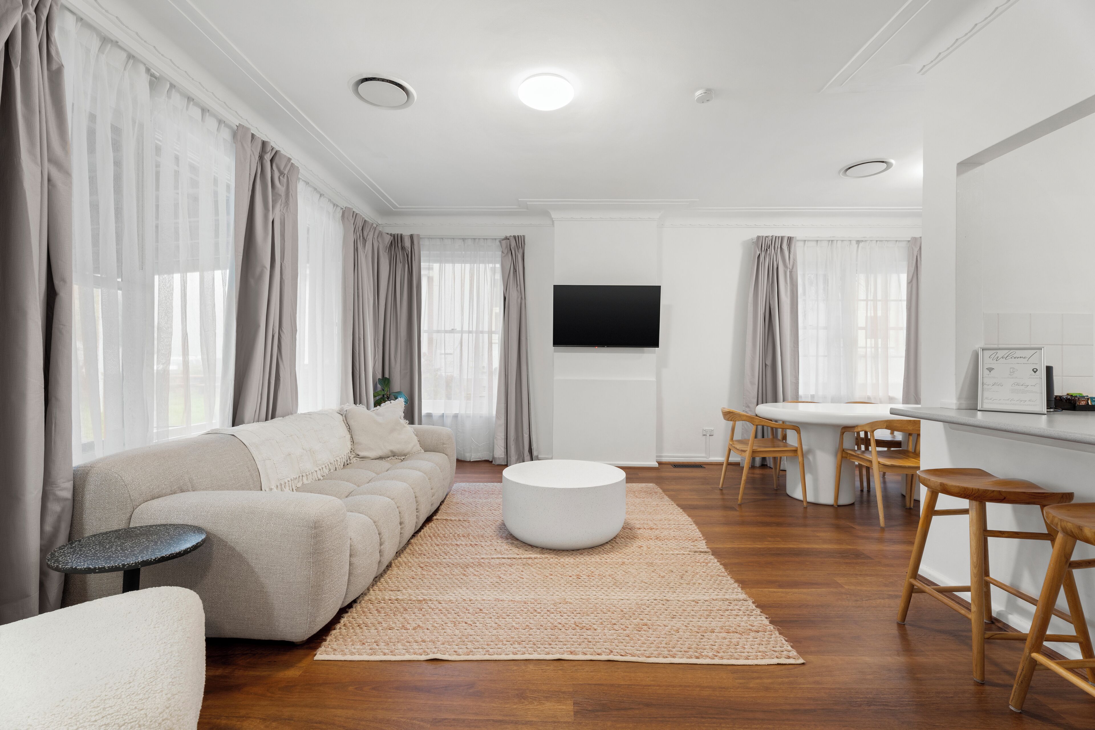 A modern living room with a beige sofa, round coffee table, and wooden chairs.