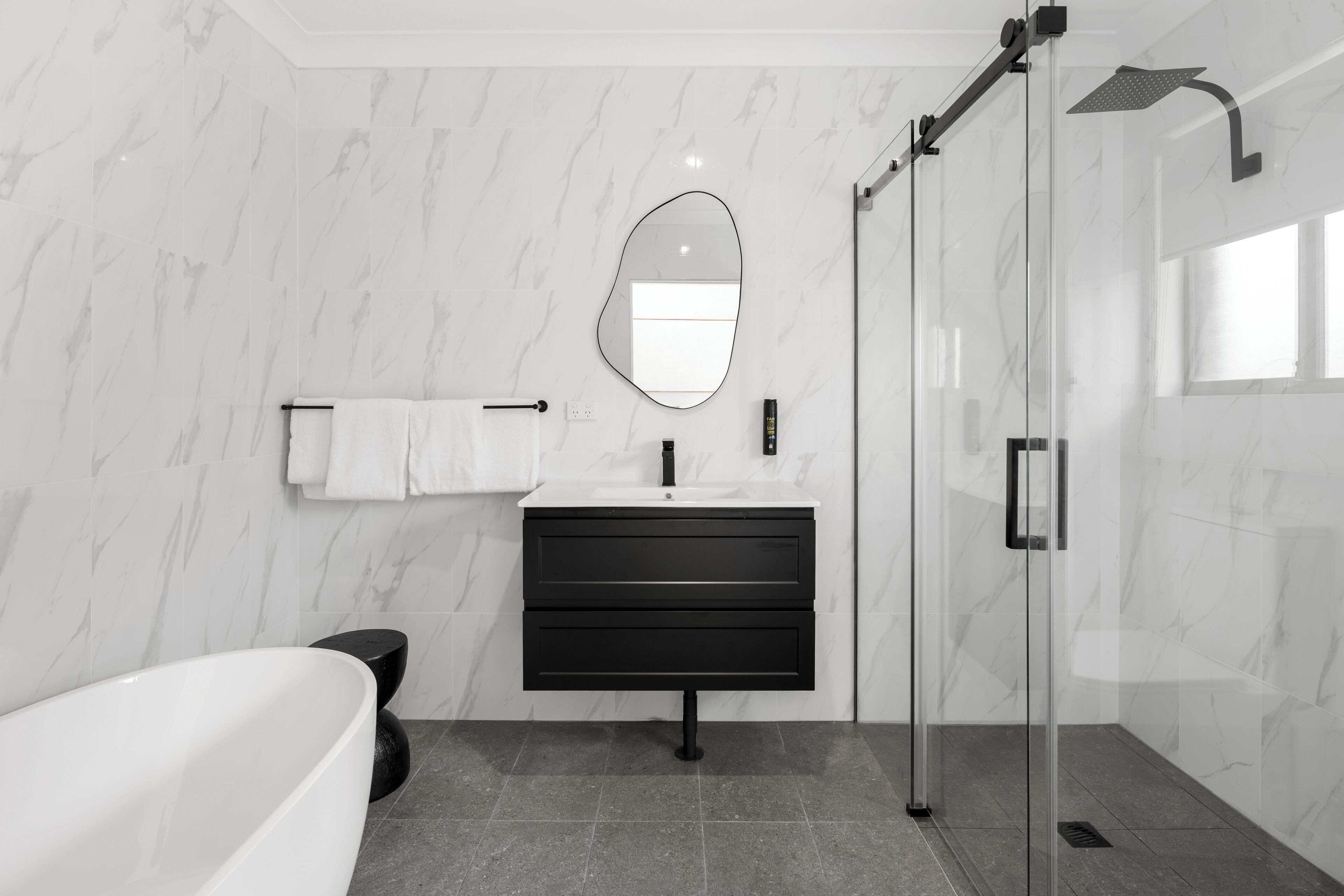 Un baño moderno con bañera, tocador con espejo y ducha con mampara de vidrio.