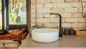 A kitchen with a white sink, a window, and a brick wall. - Montblu at Echo Point (Katoomba)