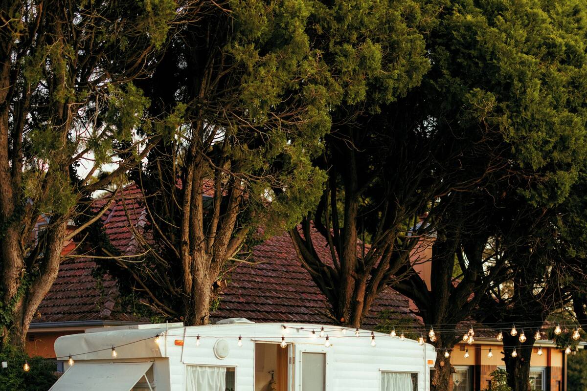 A white RV parked in a grassy area with a house in the background.