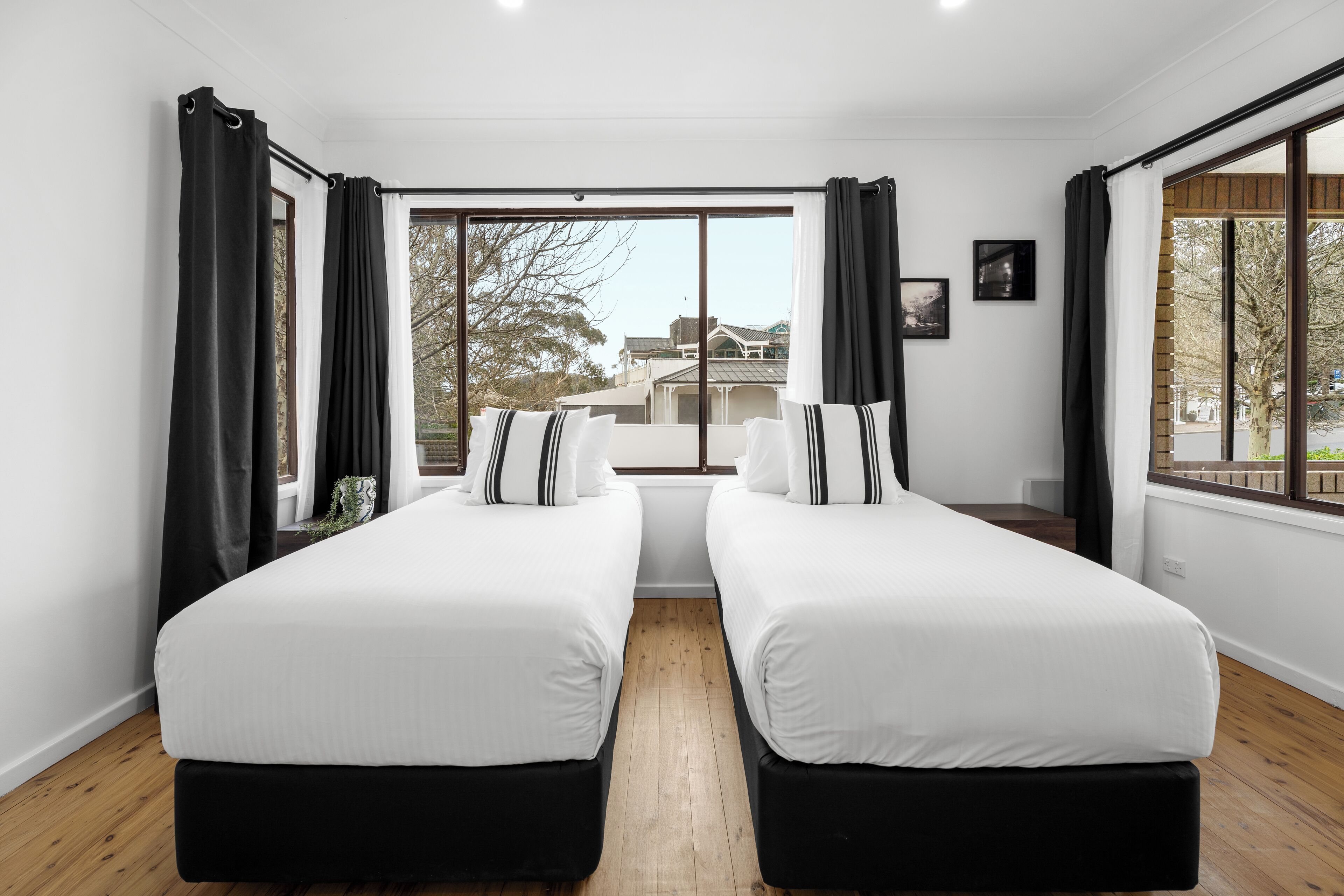 A hotel room with two beds, large windows, and a view of a building outside.