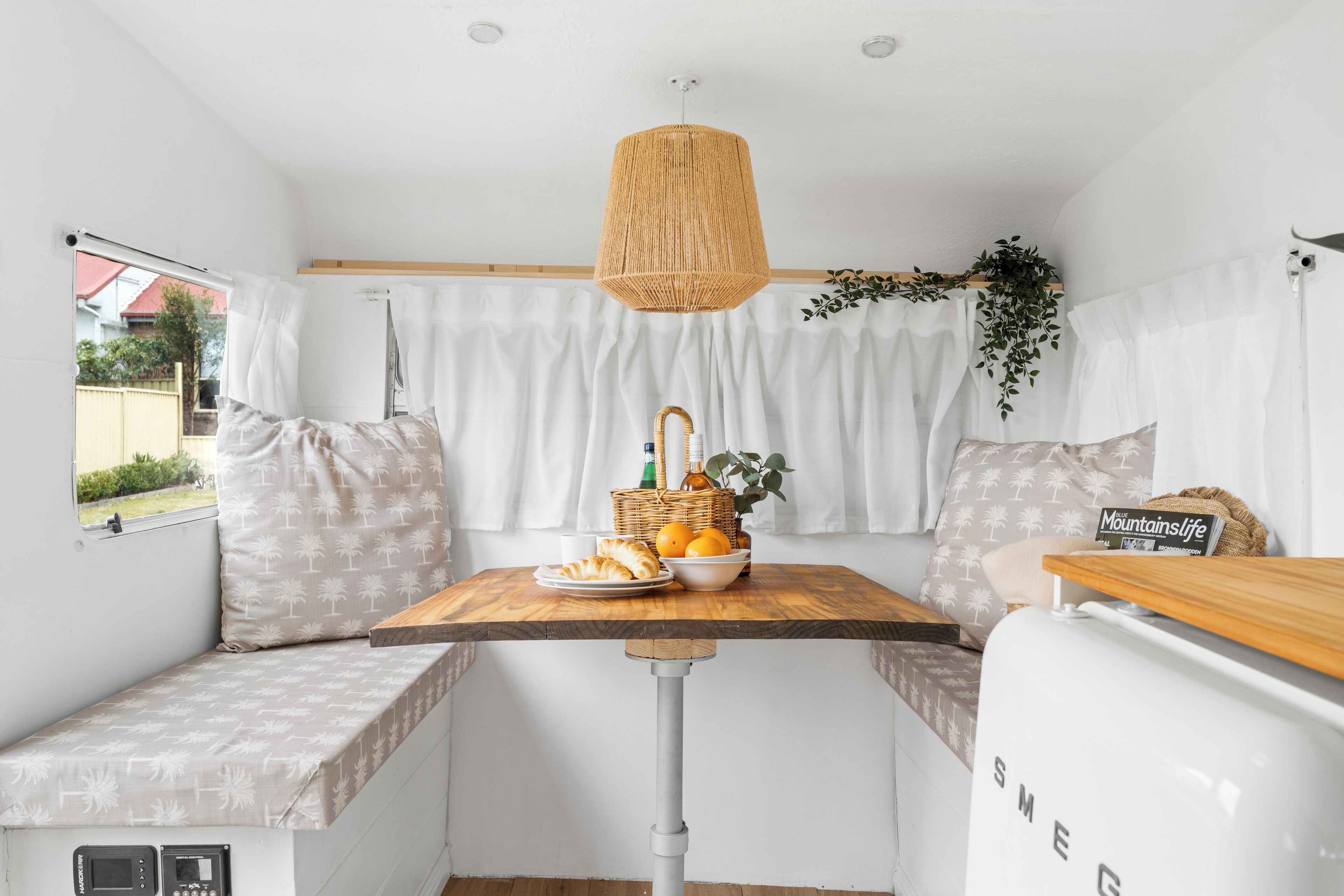 A compact living space with a wooden table, a bench, and a white refrigerator.