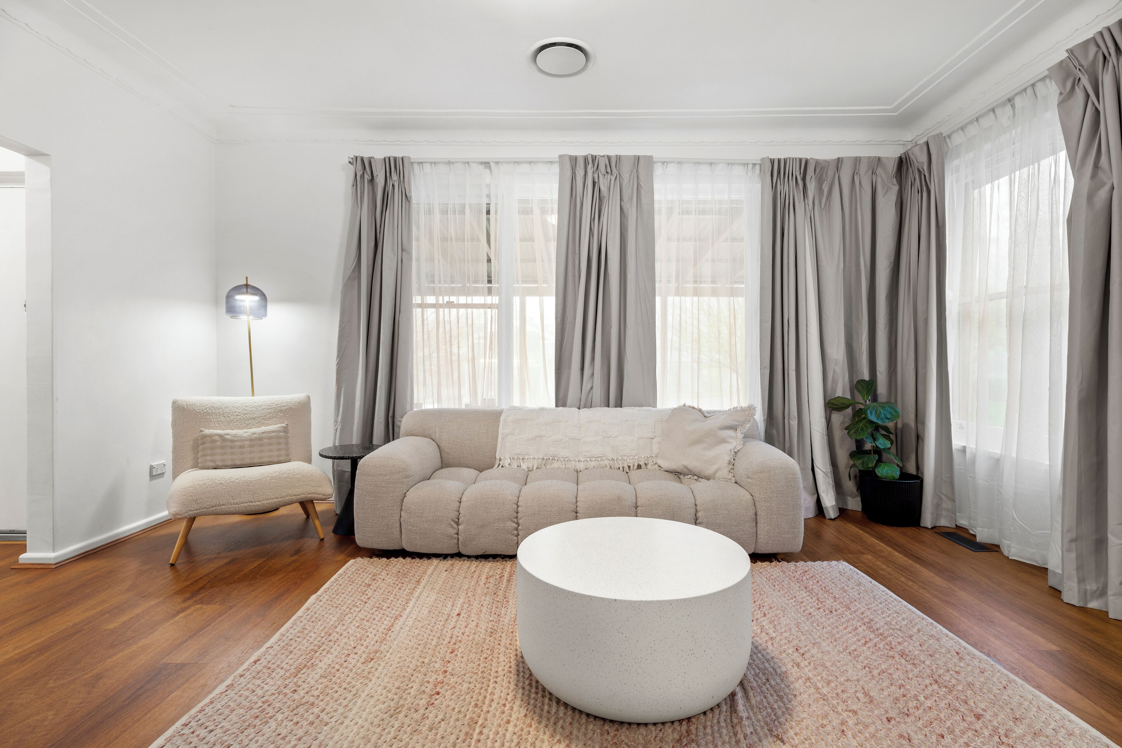 Ett modernt vardagsrum med en beige soffa, ett runt soffbord och en golvlampa.