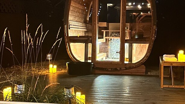 Una estructura esférica con puerta de cristal, un pequeño espacio de estar al aire libre y una fuente en primer plano.
