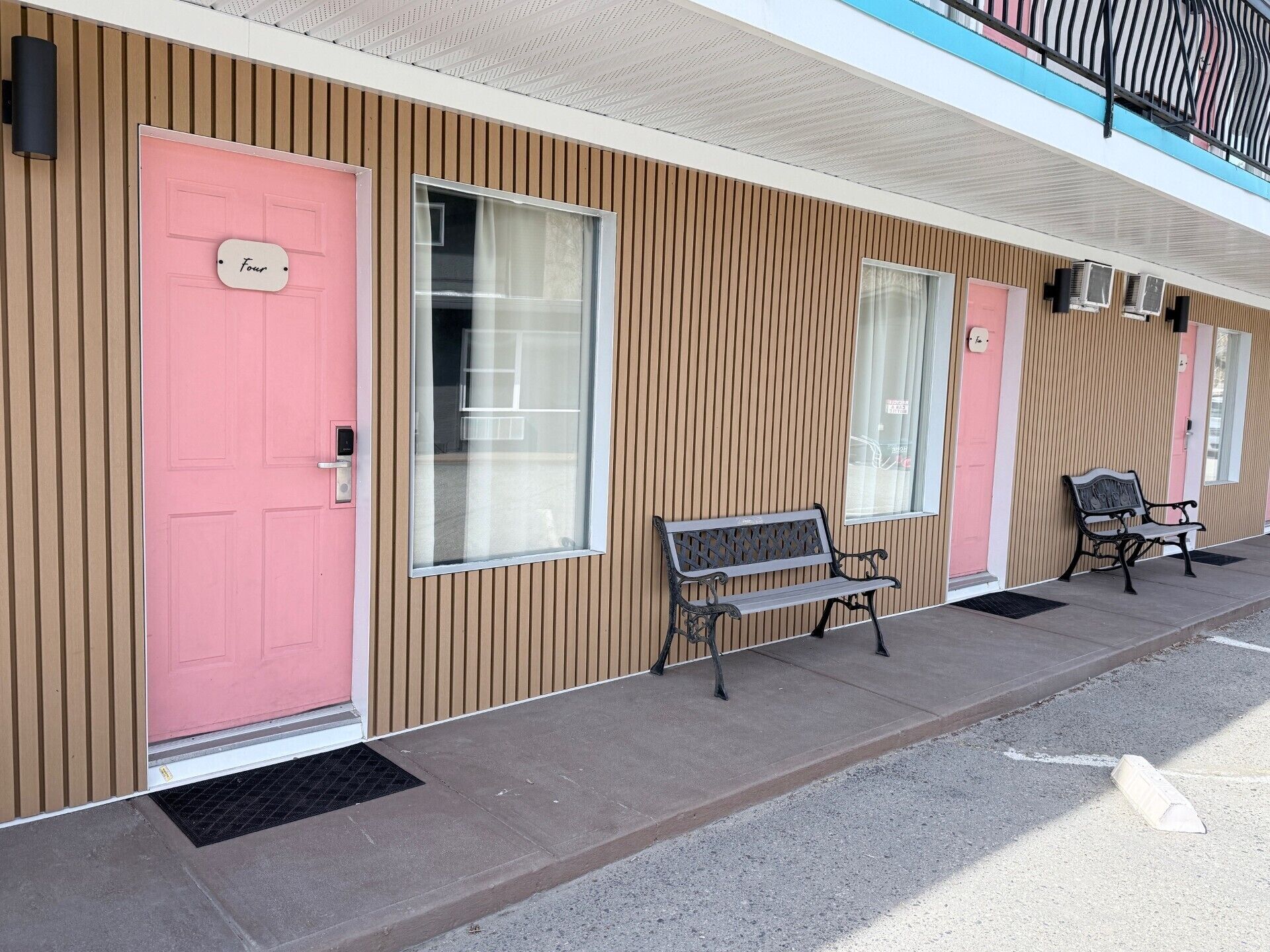 A building with a pink door labeled 'Four,' a bench, and a window.