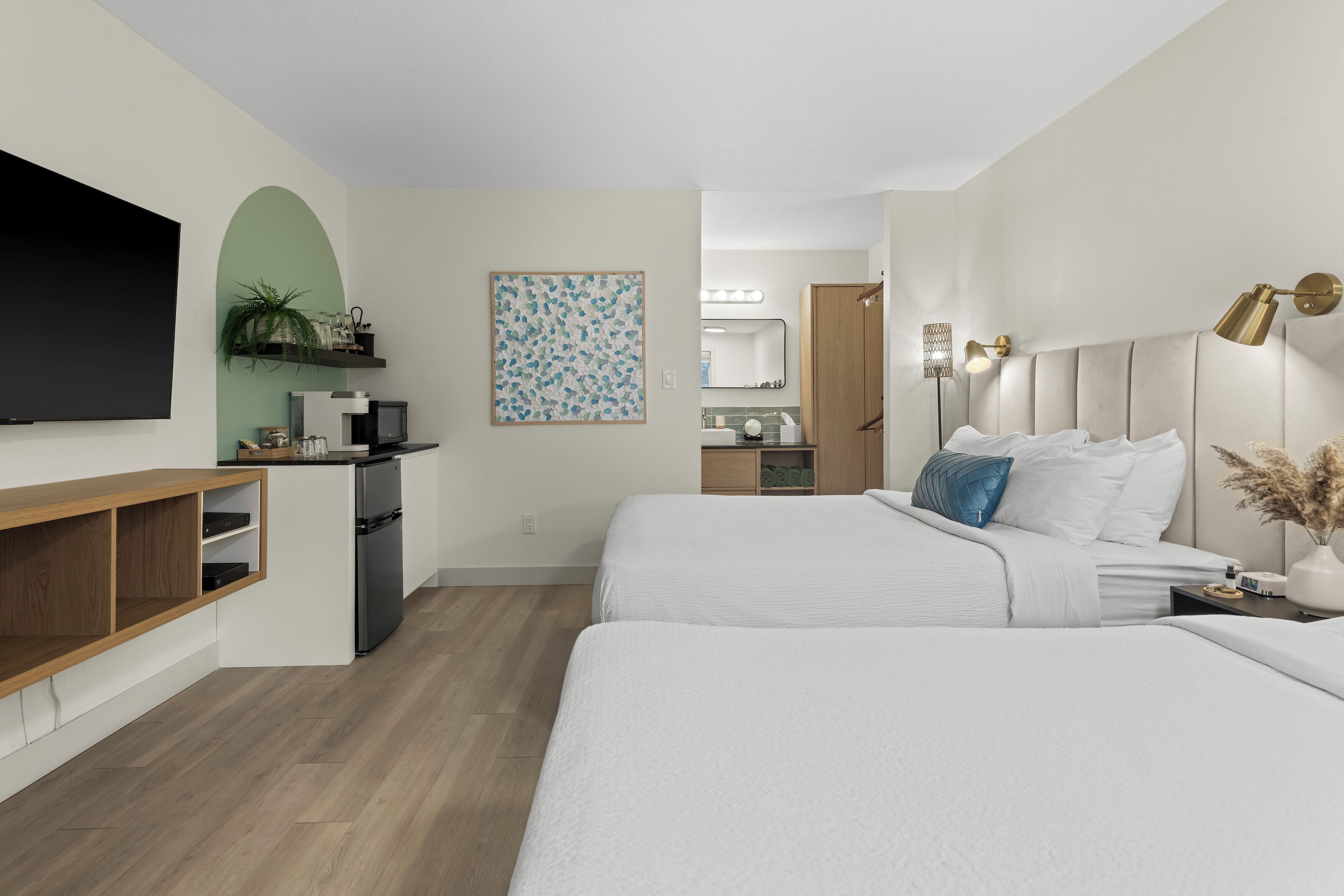 Une chambre d’hôtel moderne dotée d’une télévision à écran plat, d’un bureau avec un ordinateur, d’un lit avec une literie blanche et d’une grande fenêtre.