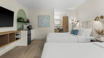 Une chambre d’hôtel moderne dotée d’une télévision à écran plat, d’un bureau avec un ordinateur, d’un lit avec une literie blanche et d’une grande fenêtre.