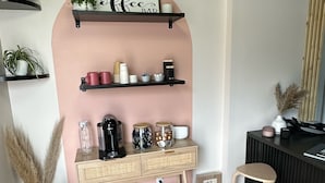 Una cocina moderna con piso de madera, una estación de café integrada y un pequeño comedor con taburetes.