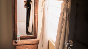 A bathroom with a wooden vanity, a towel hanging on the mirror, and a bottle of water on the counter. - Residencia San Pablo (Querétaro)