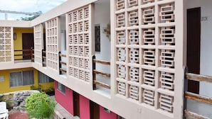 Um edifício com vários níveis, varanda, escadaria e um pequeno pátio com plantas.
